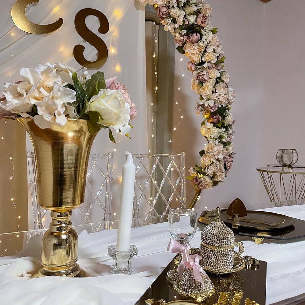 Fotowand mit Trockenblumen und Lichterketten.