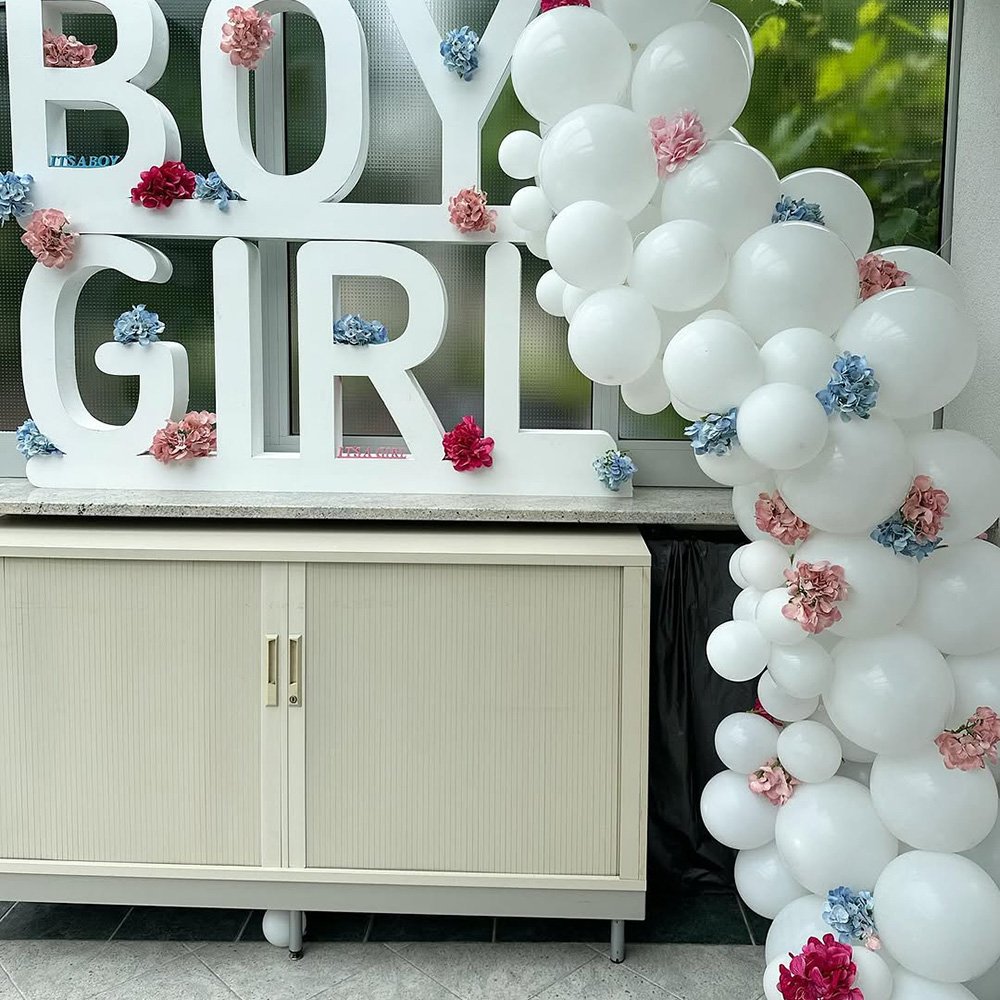 Weiße und rosafarbene Ballon-Dekoration mit dem Schriftzug „Boy or Girl“.